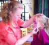 Face Painting: Small picture of Lorna painting a young girl's face at the Botanic Gardens in Edinburgh, Capital of Scotland..