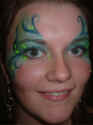 Face Painting: Adult female with blue and green swirled eye makeup with yellow highlights.