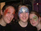 Face Painting: Three happy adult females smiling as they show off their varriously painted faces. 
