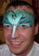 Face Painting: Adult male painted with metallic tourquoise bird mask highlighted with black.